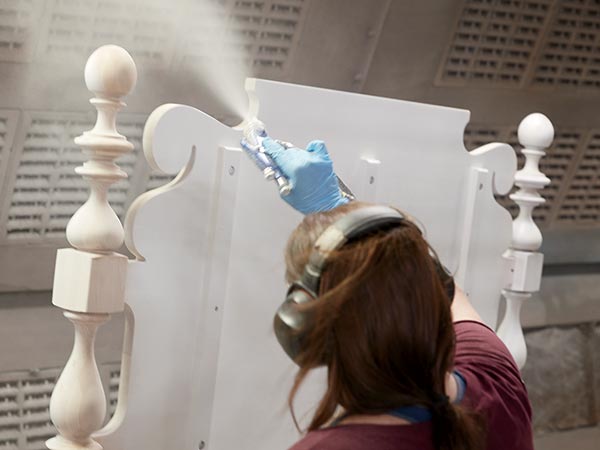 woman spray painting bed